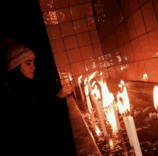 a woman lighting a candle in a dark room with tiles