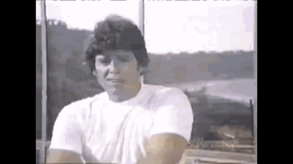 a man in a white shirt is sitting in front of a window with a view of the ocean .