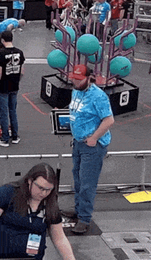 a man wearing a tie dye shirt stands in front of a robot