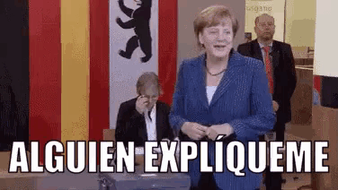 a woman in a suit is standing in front of a sign that says alguien expliqueme
