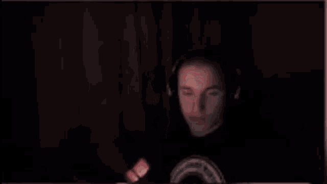 a man is sitting in front of a computer screen with his hands up in the air .