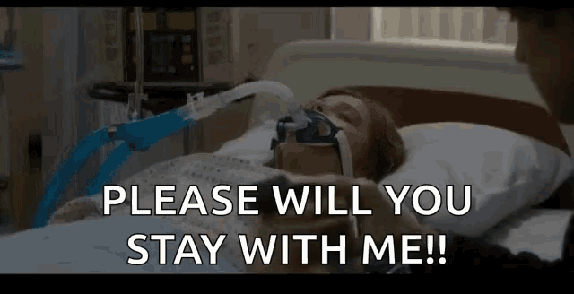 a woman is laying in a hospital bed with an oxygen mask on her face and the words please will you stay with me .