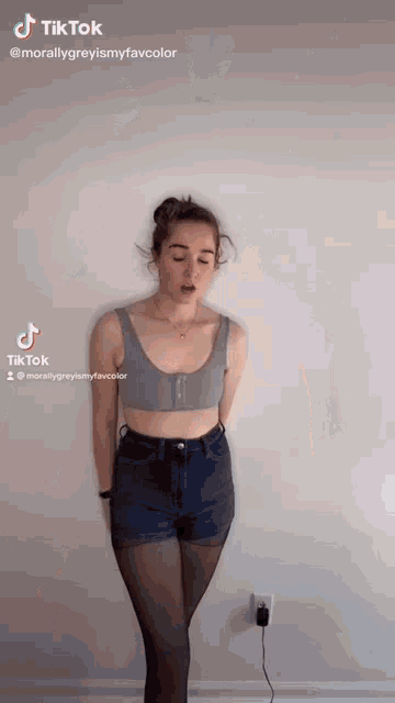 a woman is standing in front of a white wall wearing shorts and tights