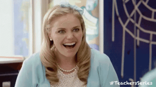 a woman wearing a blue cardigan and pearls is laughing .
