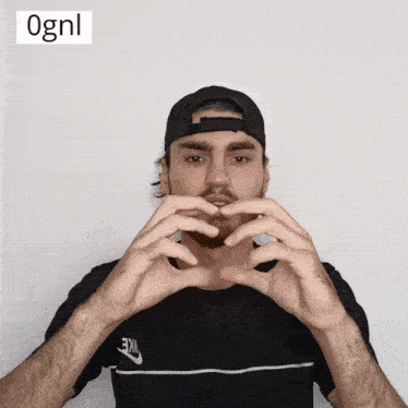 a man wearing a black nike shirt makes a heart shape with his hands