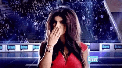 a woman in a red dress is covering her mouth with her hand in front of a crowd .