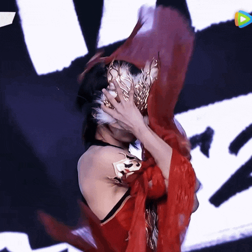a woman in a red dress is covering her face with a red cloth