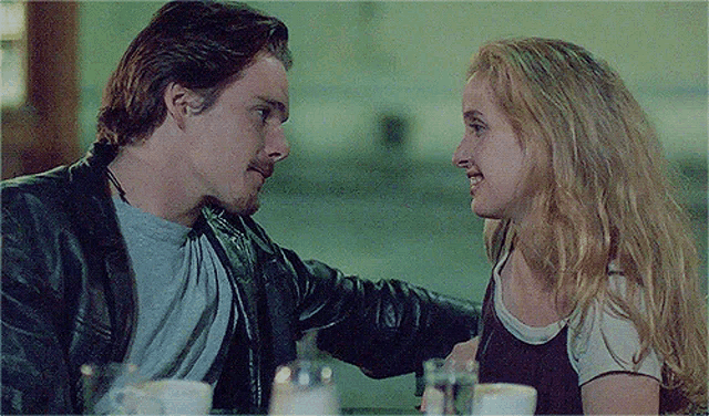a man and a woman are looking into each other 's eyes while sitting at a table .