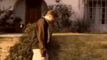 a man is standing in front of a house with a christmas tree .