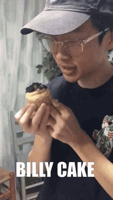 a man wearing glasses and a hat is holding a cupcake with the words billy cake below him