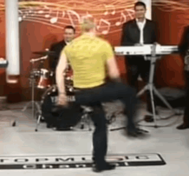 a man in a yellow shirt is dancing in front of a yamaha drum