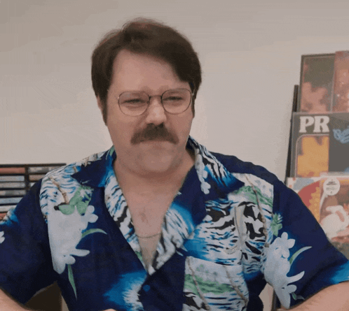 a man with glasses and a mustache wears a blue shirt that says pr on it