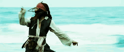 a man in a pirate costume is running in the water .