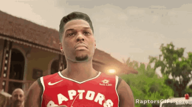 a man in a raptors jersey is standing in front of a building