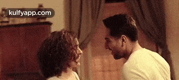 a man and a woman are looking at each other and laughing in a living room .
