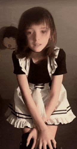 a young girl in a maid outfit is kneeling down