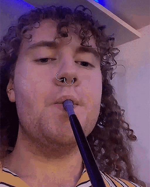 a man with curly hair is smoking a hookah with a nose ring