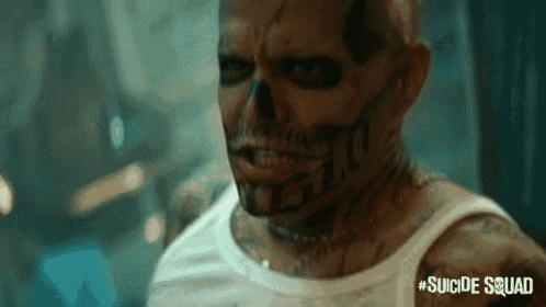 a man with a skull painted on his face is wearing a white tank top from the movie suicide squad .