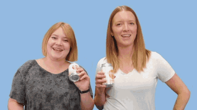 two women are laughing while holding up a can of beer that says brew dog