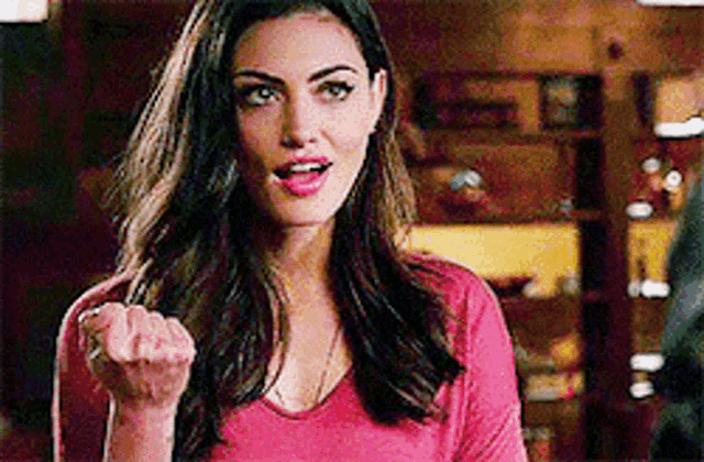 a woman in a red shirt is making a funny face while holding her fist in the air .