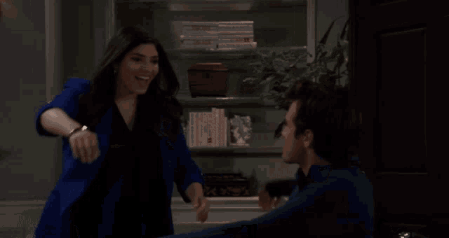 a woman in a blue jacket is dancing with a man