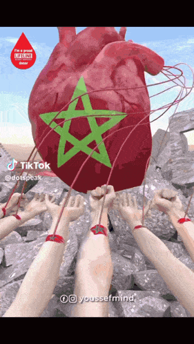 a large red heart with a green star on it is being held up by many hands