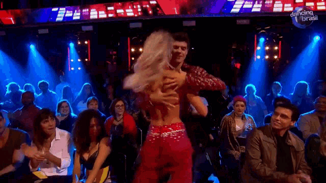 a man and a woman are dancing on stage in front of a crowd .