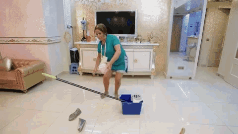 a woman cleaning the floor with a mop and bucket in a living room