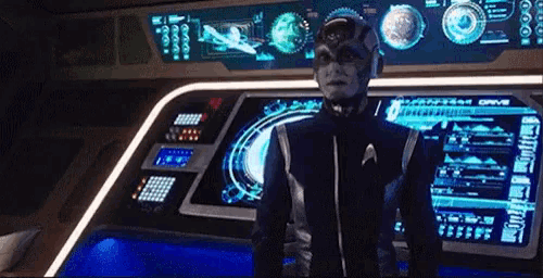 a man in a space suit is standing in front of a futuristic control panel .