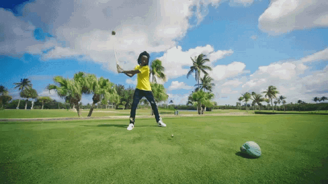 a man in a yellow shirt swings a golf club