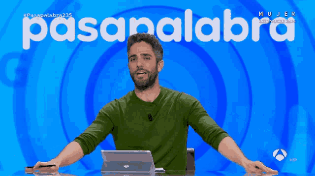 a man with his arms outstretched in front of a blue background with the word pasapalabra