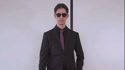 a man in a suit and tie stands in front of a white board