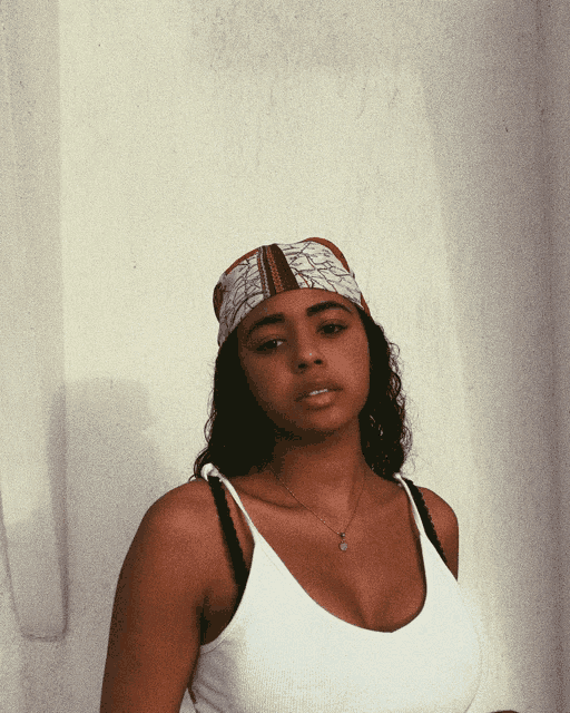 a woman wearing a scarf around her head and a white tank top
