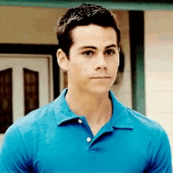 a young man wearing a blue polo shirt is standing in front of a building
