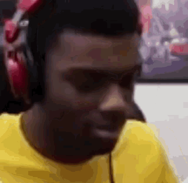 a man wearing headphones and a yellow shirt is sitting in front of a computer .