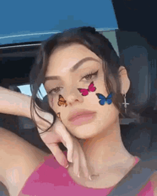 a girl with butterflies painted on her face is sitting in a car .