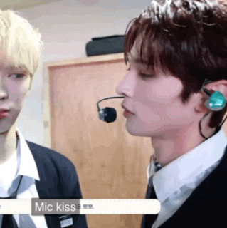 a man with a microphone on his ear is kissing another man 's neck