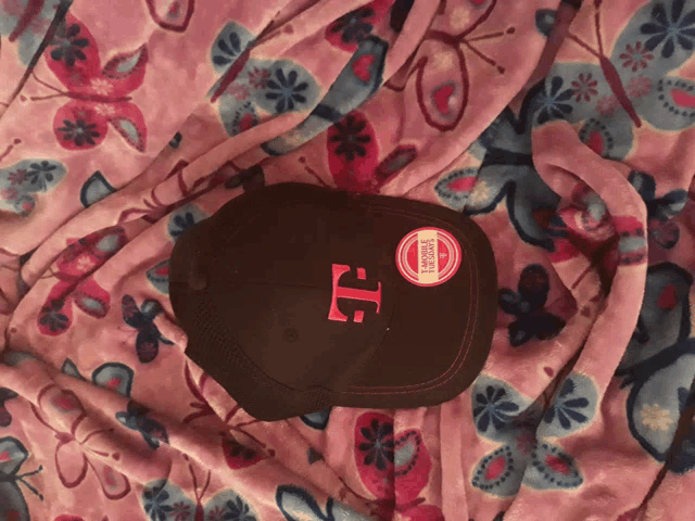 a baseball cap with a pink t on it