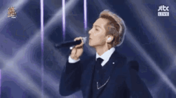 a man in a suit is singing into a microphone .