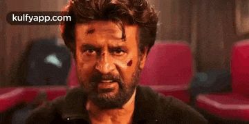 a man with a beard and a black shirt is sitting in a movie theater .