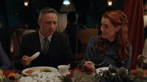 a man and a woman are sitting at a table with plates of food
