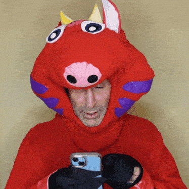 a man in a red monster costume holds a cell phone