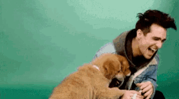 a man is laughing while playing with a puppy .