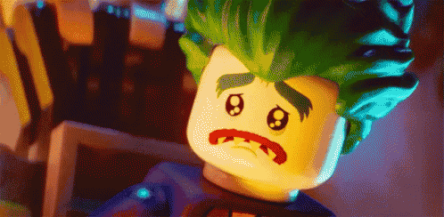 a lego joker with green hair and a sad face .