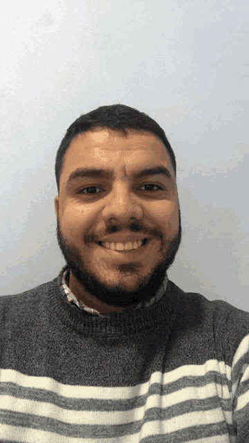a man with a beard is wearing a striped sweater and smiling