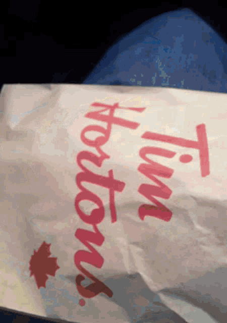 a tim hortons bag is sitting on a person 's lap