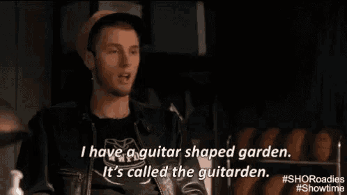 a man in a hat and leather jacket is talking about having a guitar shaped garden .