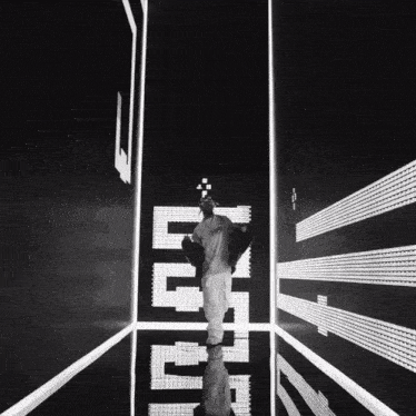 a black and white photo of a man walking through a room with the word tetris written on the wall