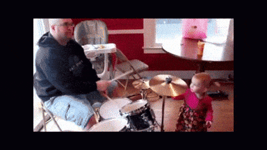 a man and a baby are playing drums in a room
