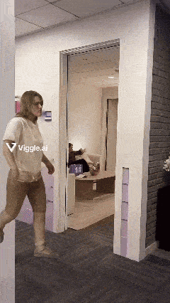a woman walking through a hallway with a sign that says wiggle.ai on it